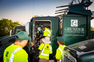 service truck with branded logo grunder landscaping surrounded by landscape workers 