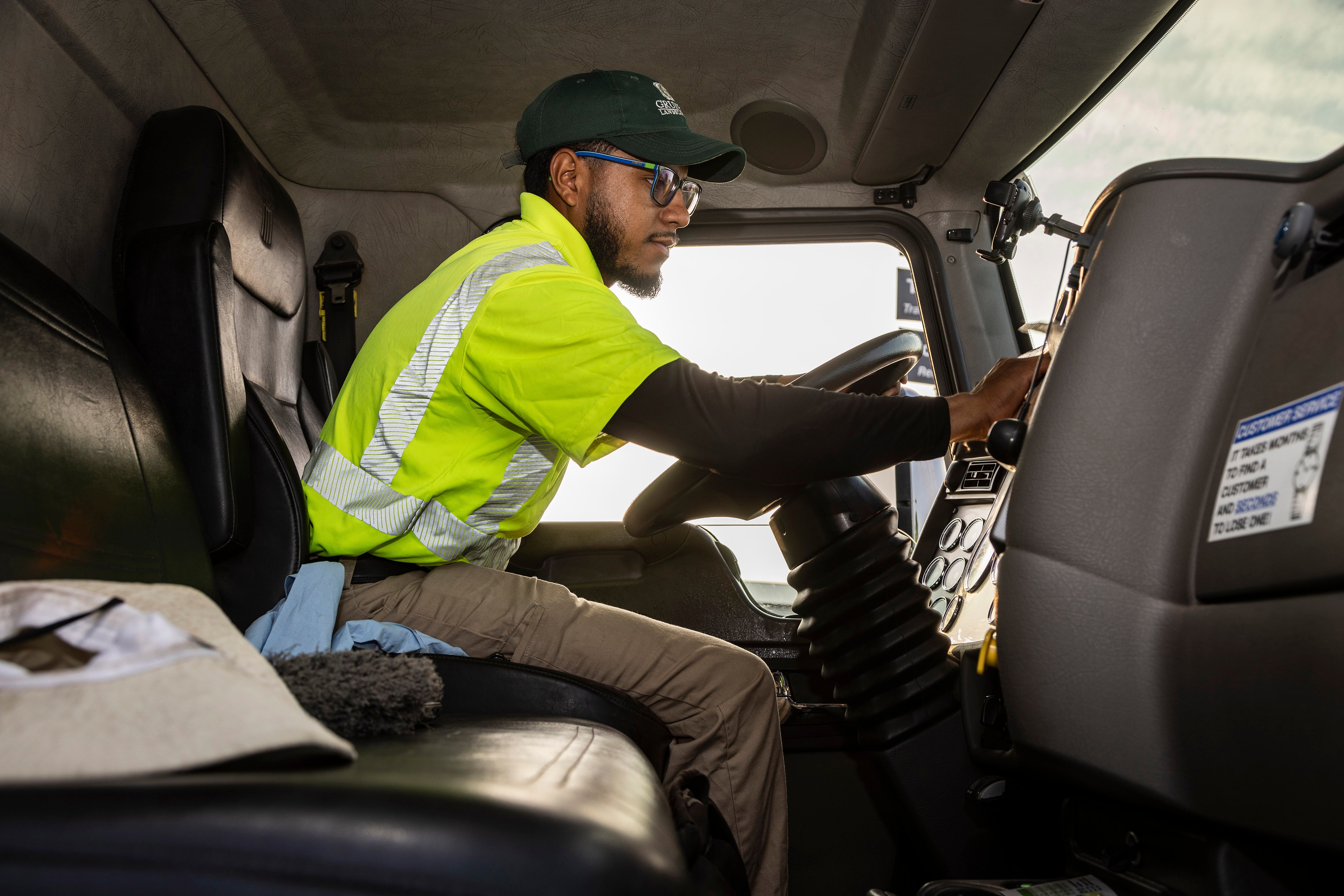 Landscaping employee in a safety vest preparing to drive a truck for their landscaping business